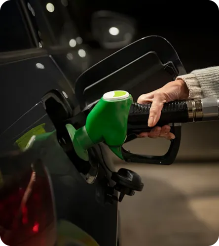 Close-up of a hand using a green fuel pump nozzle to refuel a vehicle, representing alternative fuels and sustainable energy solutions.
